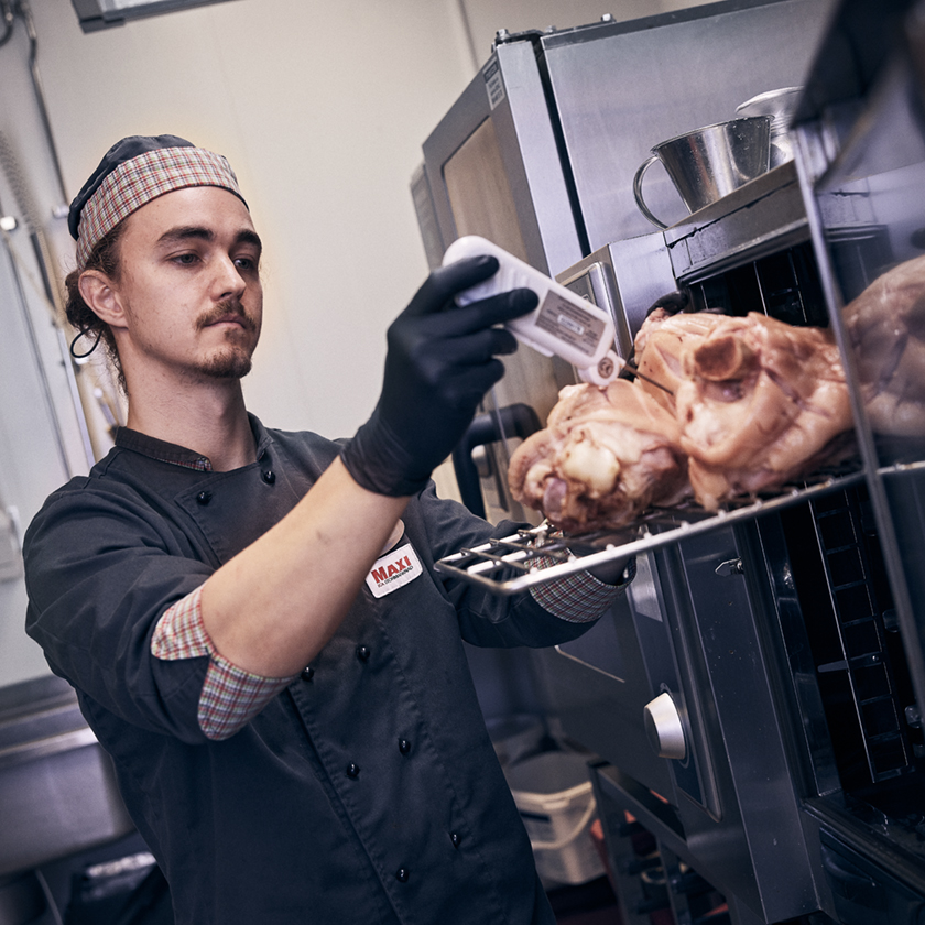 Kitchen staff cooking and checking the temperature of the meat